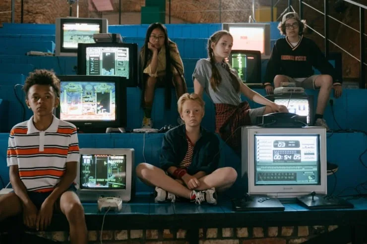 Kids sitting in front of old TVs and game screens